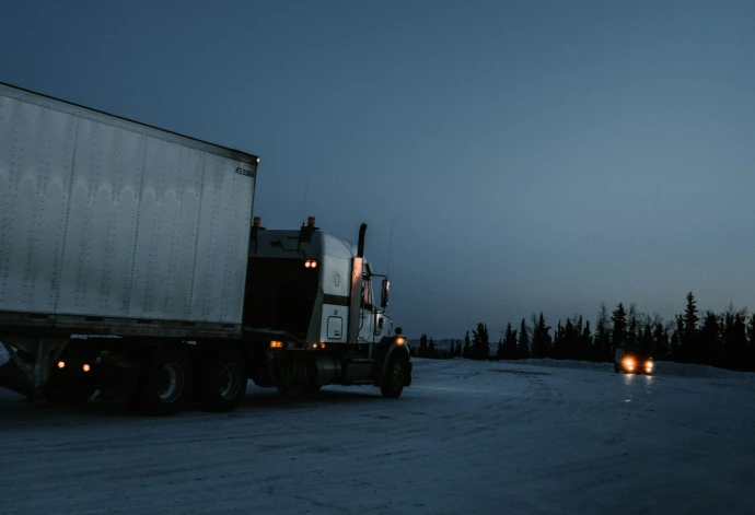 white and black freight truck traveling on road
